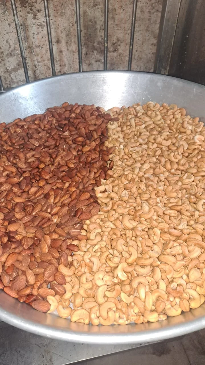 Almonds and cashews arranged side by side in a large metal tray.