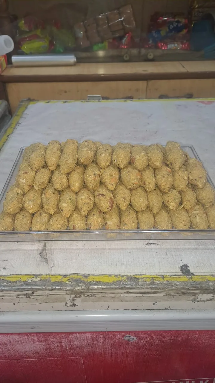Rows of oval sweets with visible nuts and seeds in a display tray.