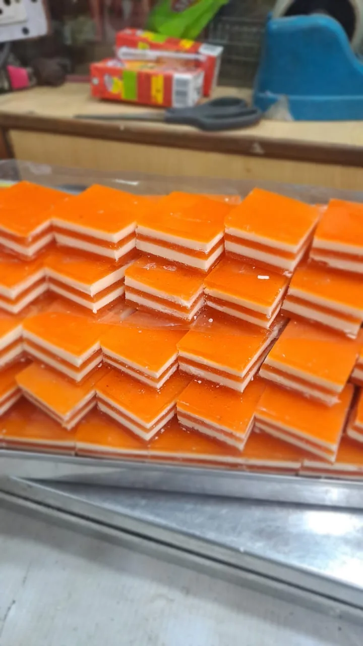 Orange and white layered sweets cut into rectangles on a tray.