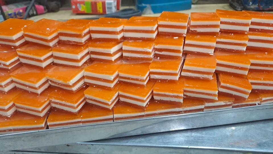 Rows of orange and white layered sweets on a metal tray.