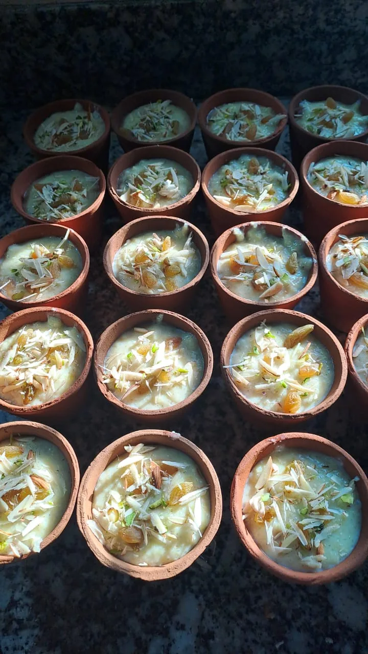 Rows of creamy desserts topped with nuts in small clay cups.