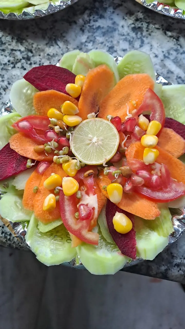 A salad plate with cucumber, carrot, beetroot, tomato, corn and lemon.