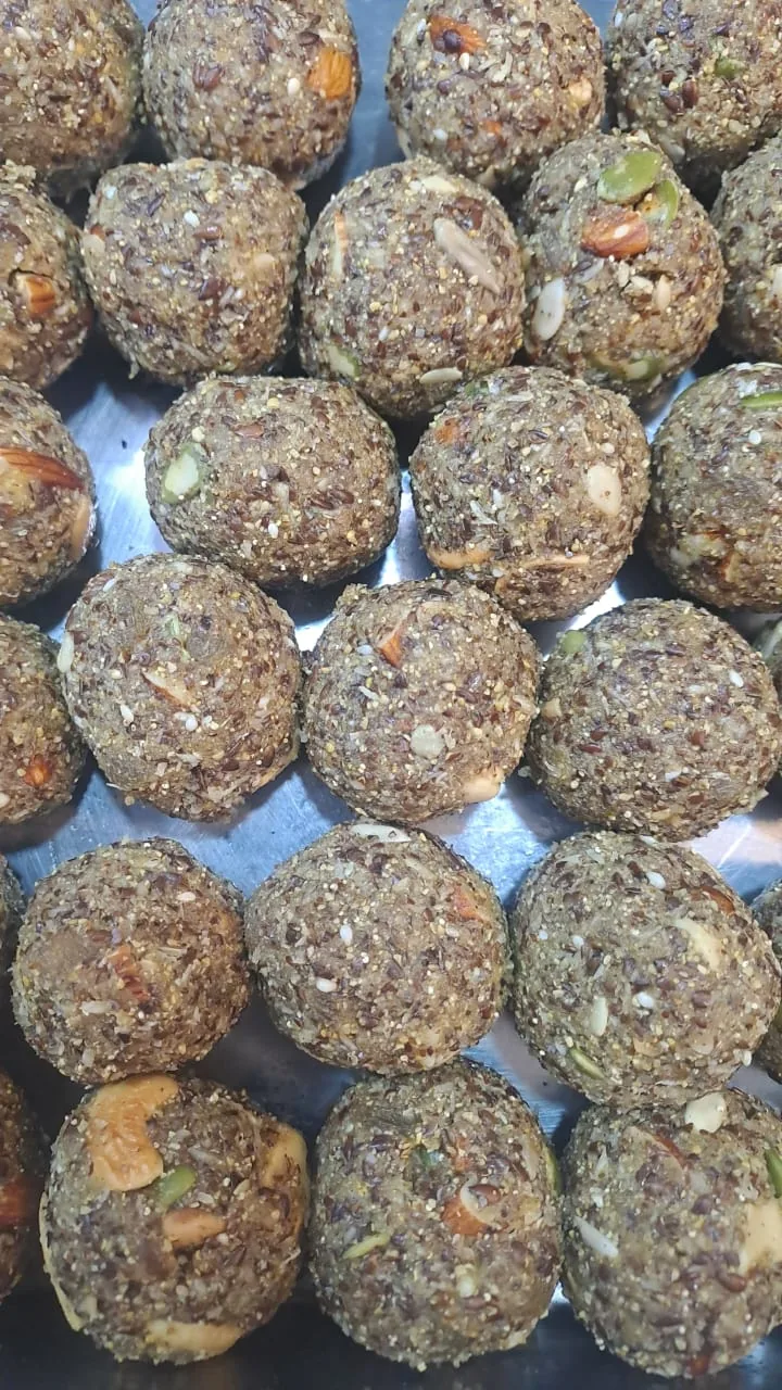 Round laddoos with visible nuts and seeds arranged on a tray.