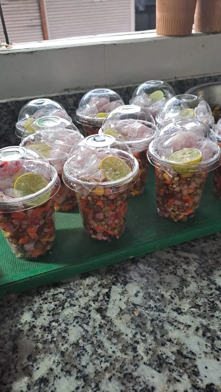 Lidded takeaway cups of mixed salad topped with lemon halves.