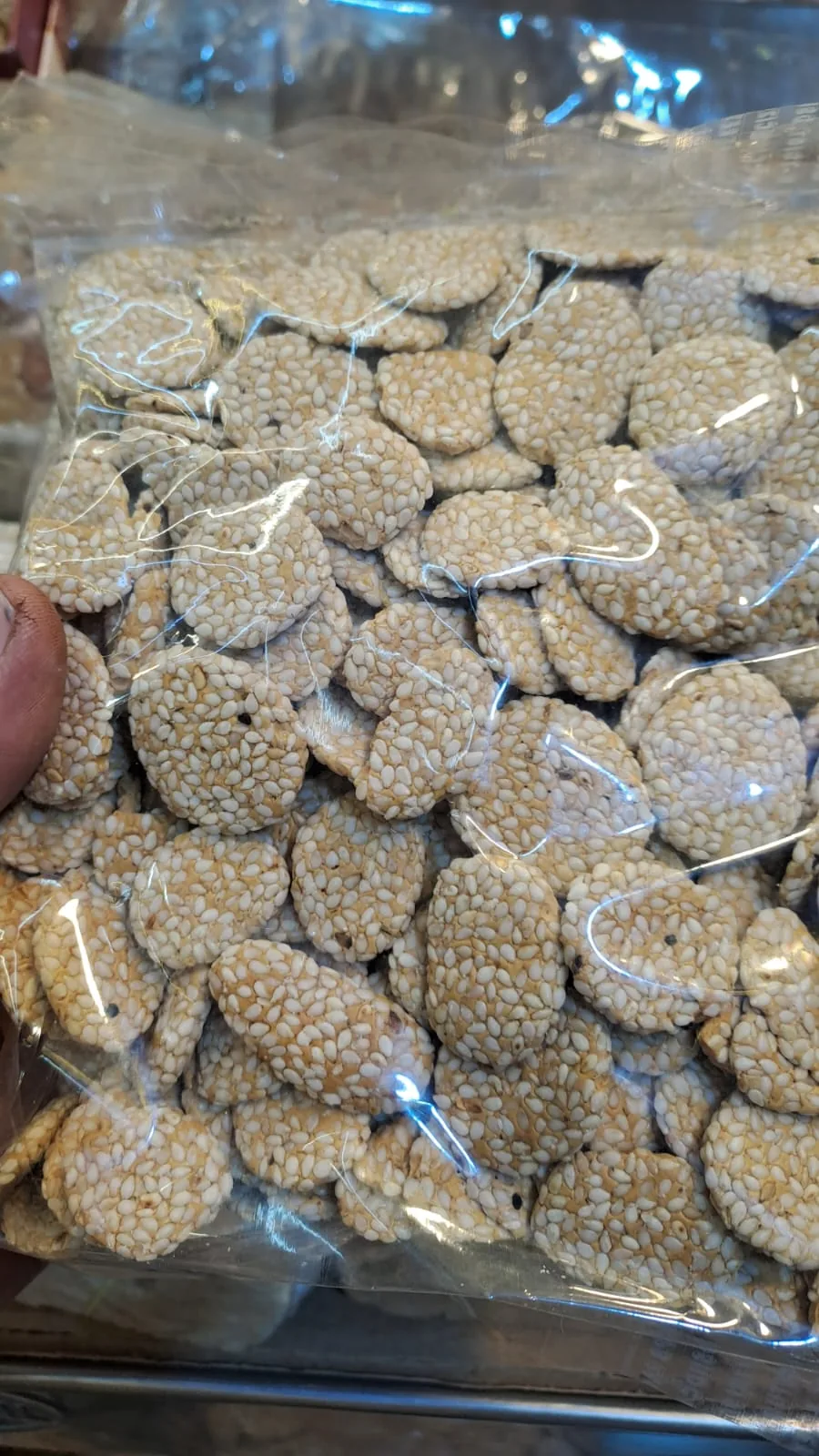 A clear bag filled with small round sesame-coated rewri.
