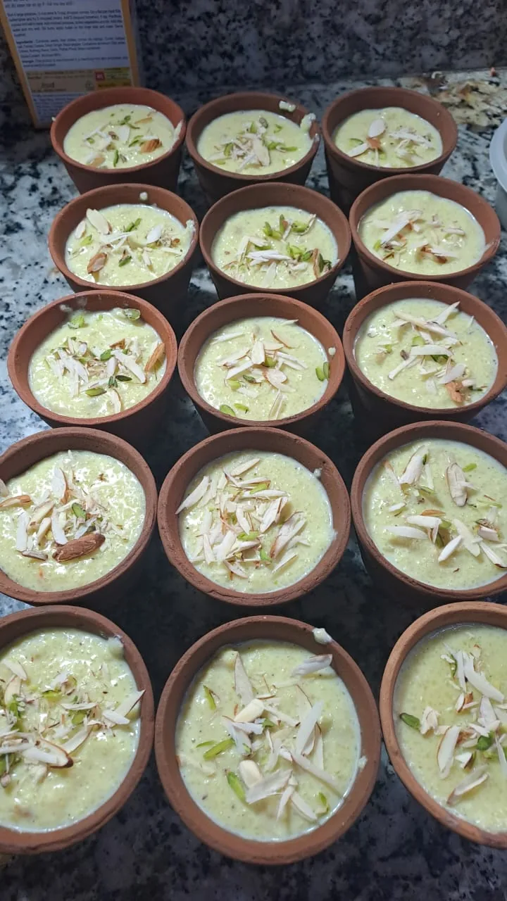 A batch of creamy desserts garnished with sliced nuts in clay cups.