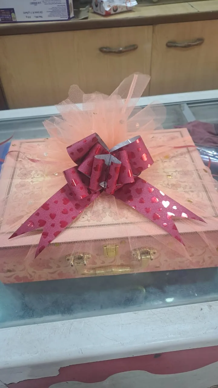 A rectangular gift hamper wrapped in pink netting with a ribbon bow.