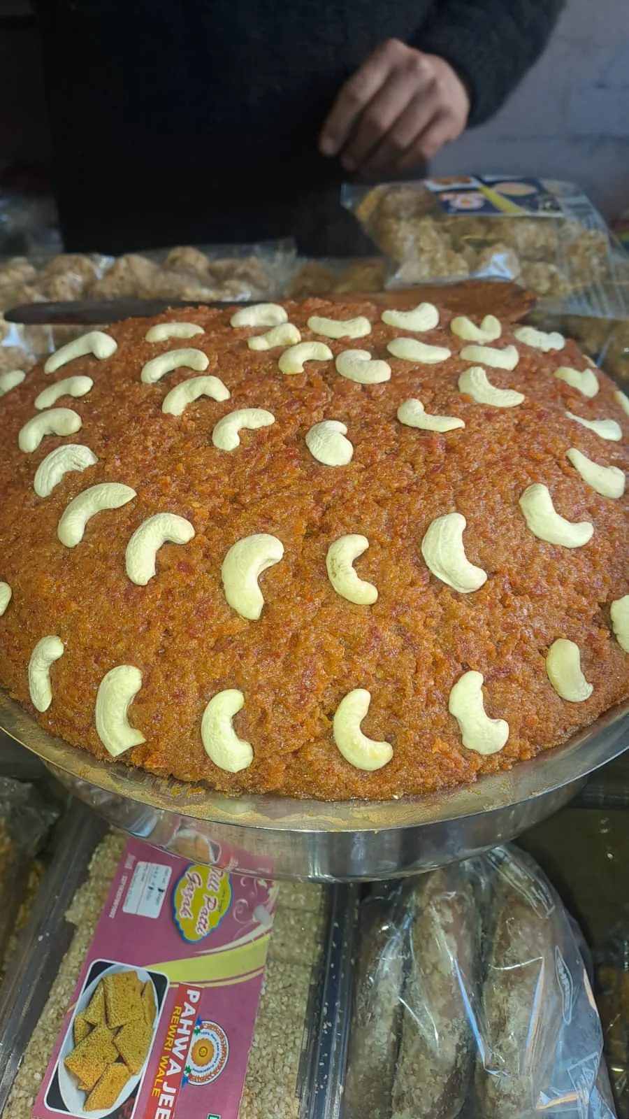 A large mound of orange carrot halwa decorated with whole cashews.